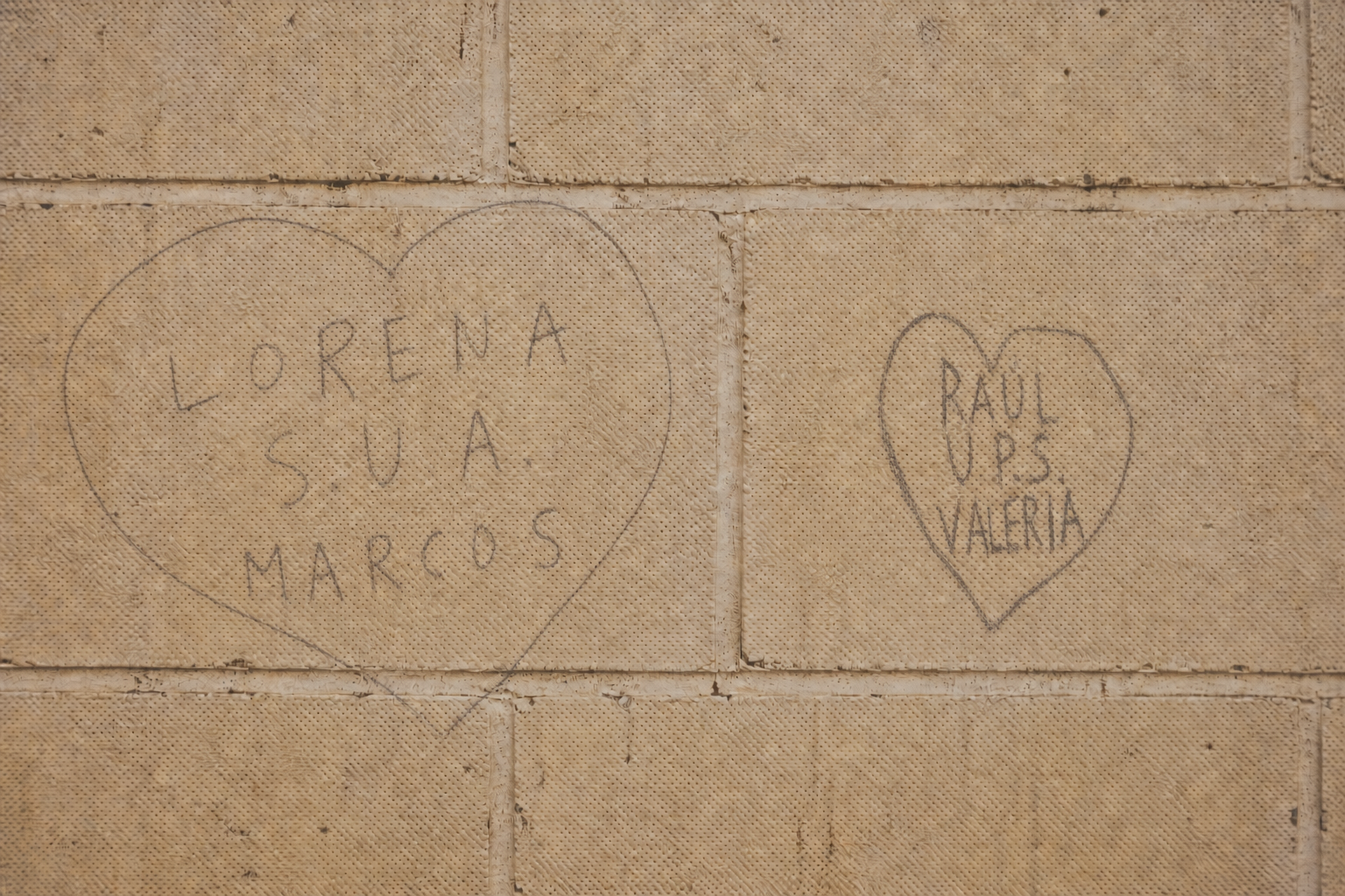 Corazones y nombres escritos en una pared de escuela
